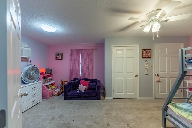 interior space with light carpet, a textured ceiling, a wall mounted AC, and ceiling fan