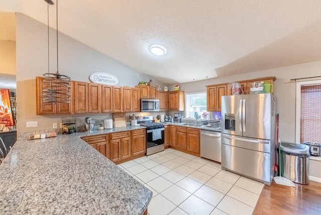 kitchen featuring sink, hanging light fixtures, vaulted ceiling, light tile patterned flooring, and stainless steel appliances