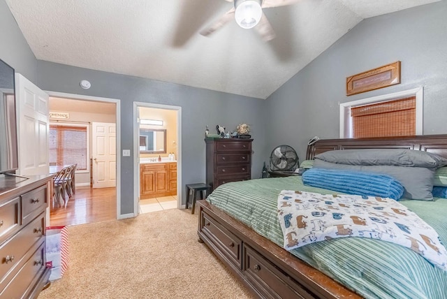 carpeted bedroom with ceiling fan, lofted ceiling, and ensuite bath