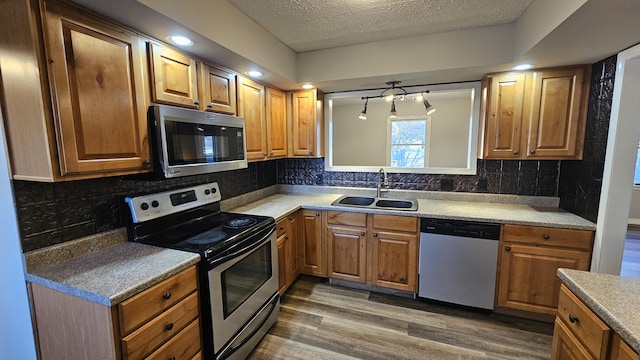 kitchen featuring decorative backsplash, appliances with stainless steel finishes, a textured ceiling, dark wood-type flooring, and sink