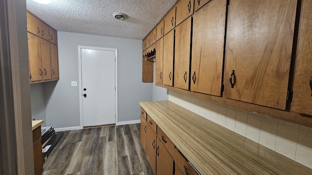 laundry room featuring dark wood-type flooring and a textured ceiling