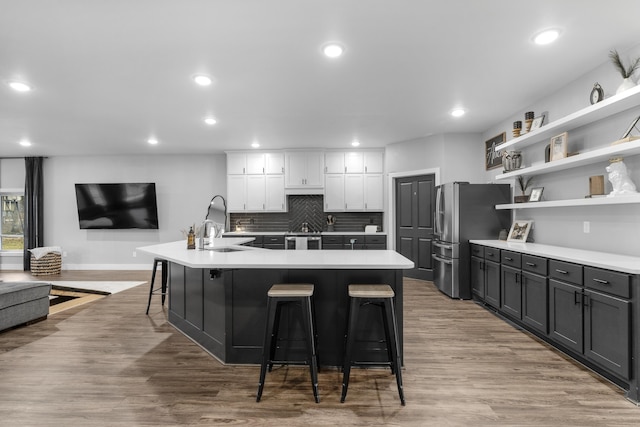 kitchen with a kitchen breakfast bar, white cabinets, a spacious island, and light wood-type flooring