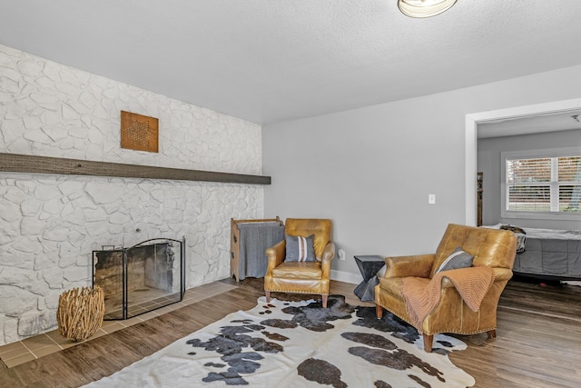 living area featuring a fireplace, wood-type flooring, and a textured ceiling