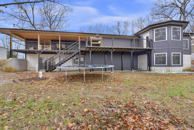 back of property with a wooden deck and a trampoline