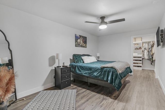 bedroom with wood-type flooring, a closet, a spacious closet, and ceiling fan