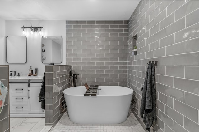 bathroom with vanity, a tub to relax in, and tile walls