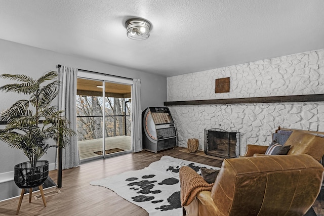 living room with a fireplace, hardwood / wood-style floors, and a textured ceiling