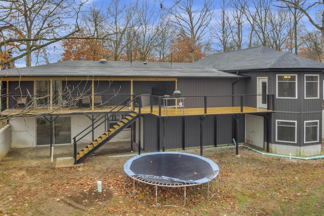 back of house with a wooden deck and a trampoline