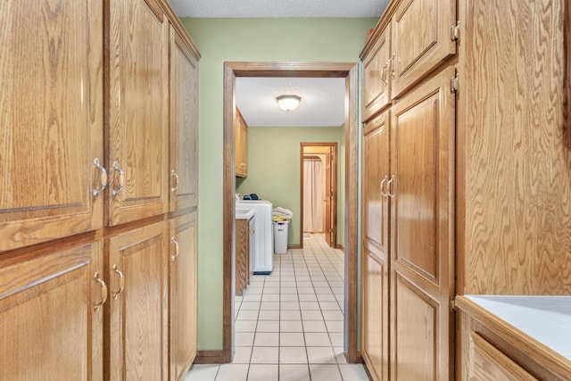 corridor with light tile patterned flooring, a textured ceiling, and washing machine and clothes dryer