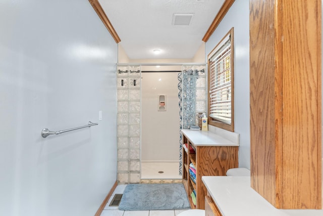 bathroom with tile patterned floors, toilet, ornamental molding, a textured ceiling, and walk in shower