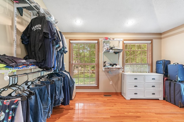 walk in closet with light hardwood / wood-style floors and vaulted ceiling