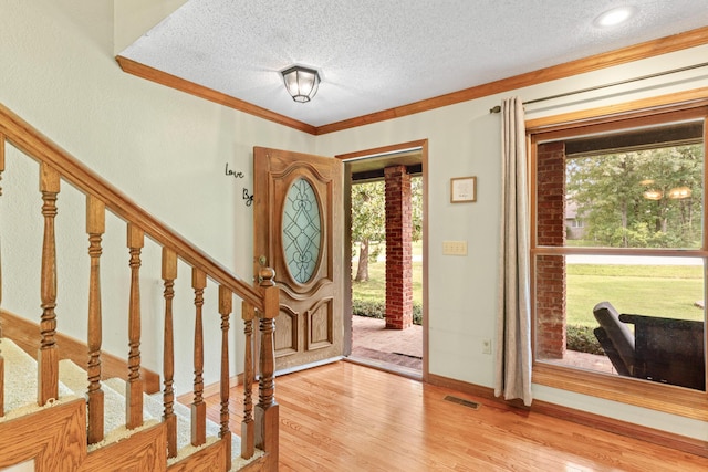 entryway featuring hardwood / wood-style floors, a textured ceiling, and crown molding