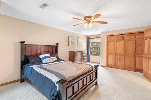 bedroom with ceiling fan, light colored carpet, a textured ceiling, and a closet