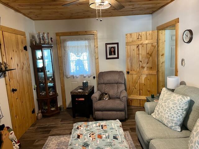 sitting room featuring a barn door, ceiling fan, dark hardwood / wood-style flooring, and wood ceiling