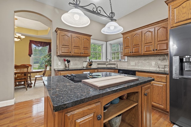 kitchen with a center island, black appliances, sink, tasteful backsplash, and decorative light fixtures