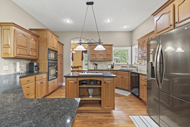 kitchen with a center island, sink, backsplash, pendant lighting, and black appliances