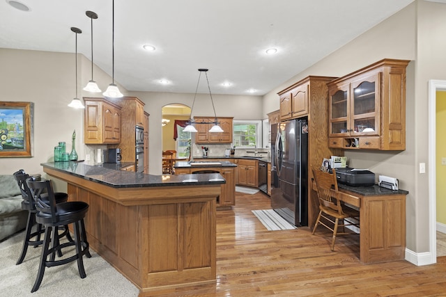 kitchen featuring sink, hanging light fixtures, kitchen peninsula, a breakfast bar area, and black appliances