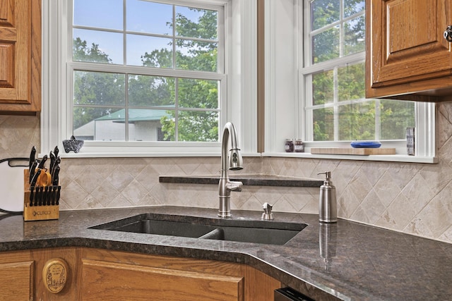 kitchen featuring backsplash, dark stone countertops, and sink