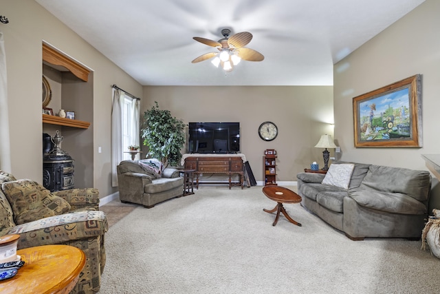 carpeted living room with a wood stove and ceiling fan