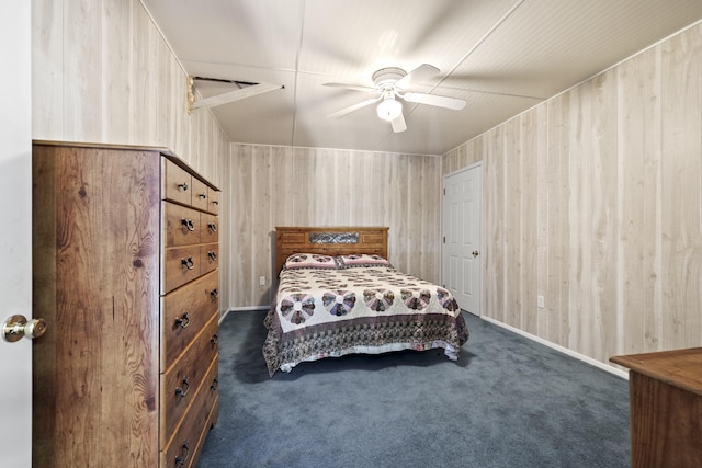 bedroom with dark carpet, ceiling fan, and wood walls