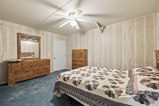 bedroom featuring ceiling fan, wood walls, and dark colored carpet