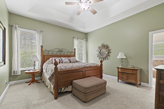 bedroom featuring a tray ceiling, ceiling fan, and light carpet