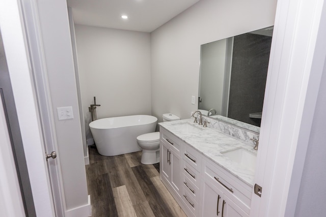 bathroom featuring vanity, toilet, wood-type flooring, and a tub to relax in