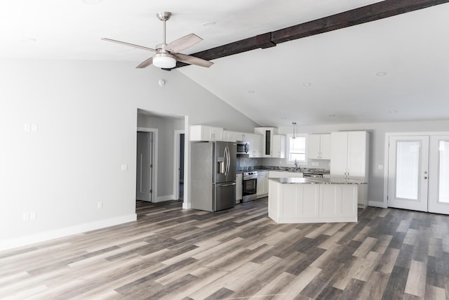 kitchen with a center island, lofted ceiling with beams, ceiling fan, appliances with stainless steel finishes, and white cabinetry