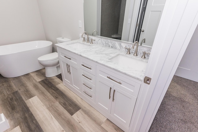 bathroom featuring a bathing tub, hardwood / wood-style floors, vanity, and toilet