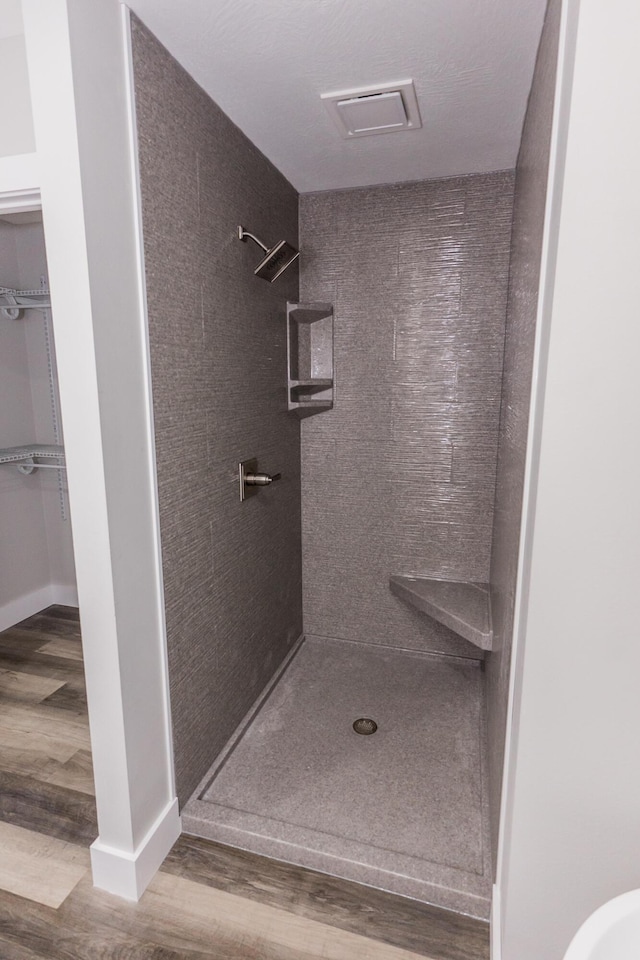 bathroom with hardwood / wood-style flooring and walk in shower