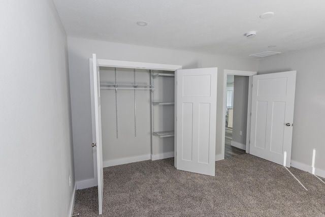 unfurnished bedroom featuring dark carpet and a closet