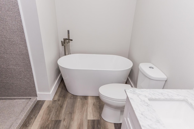 bathroom featuring a bath, vanity, hardwood / wood-style flooring, and toilet