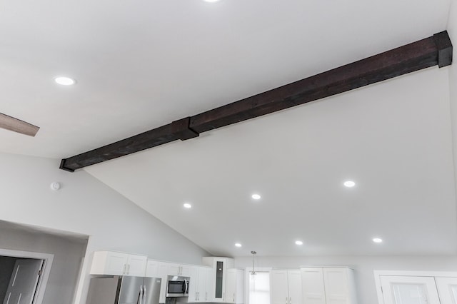 interior details featuring white cabinets, appliances with stainless steel finishes, and beamed ceiling