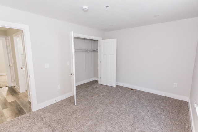 unfurnished bedroom with a closet and light colored carpet