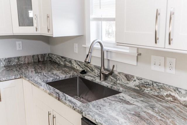 details with white cabinetry, sink, and light stone counters