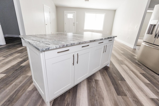 kitchen featuring light stone countertops, stainless steel refrigerator with ice dispenser, dark hardwood / wood-style flooring, white cabinets, and a kitchen island