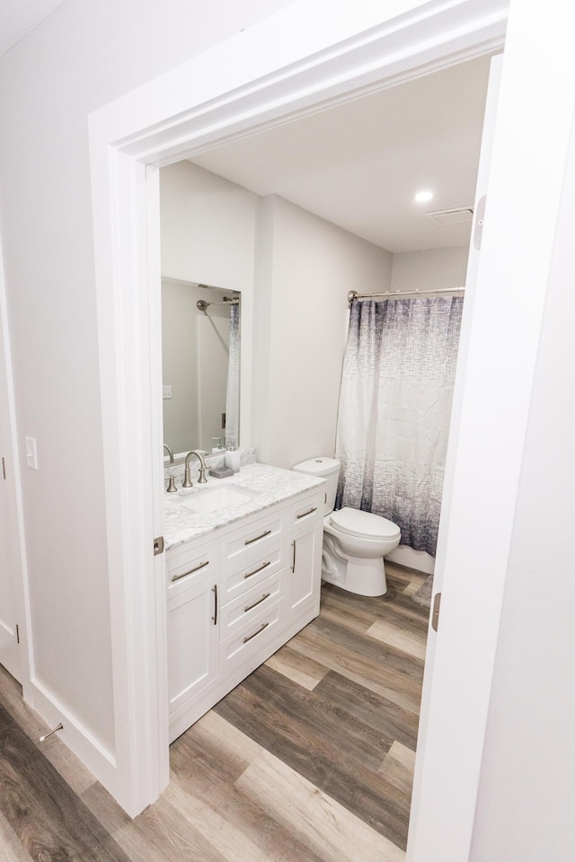 bathroom featuring wood-type flooring, vanity, toilet, and curtained shower