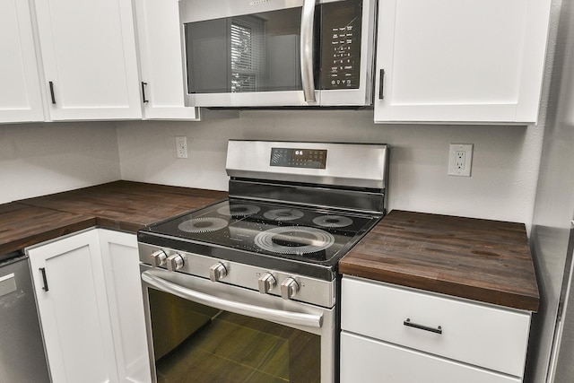 kitchen featuring wooden counters, appliances with stainless steel finishes, and white cabinetry