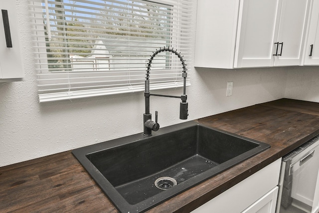 details with butcher block counters, sink, white cabinets, and stainless steel dishwasher