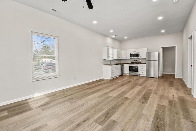 kitchen with white cabinets, sink, ceiling fan, light hardwood / wood-style floors, and stainless steel appliances