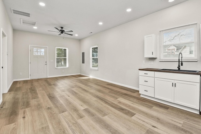 unfurnished living room featuring ceiling fan, sink, and light hardwood / wood-style flooring