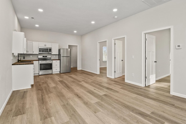 kitchen featuring appliances with stainless steel finishes, light hardwood / wood-style flooring, and white cabinetry