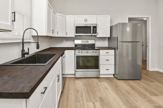 kitchen with light hardwood / wood-style floors, sink, white cabinetry, and stainless steel appliances