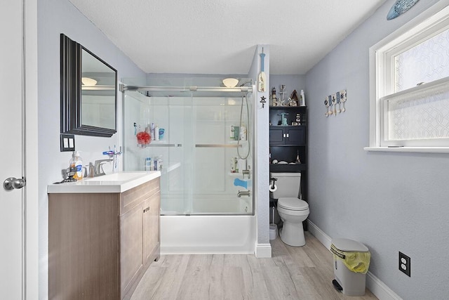 full bathroom featuring bath / shower combo with glass door, a textured ceiling, toilet, vanity, and hardwood / wood-style flooring