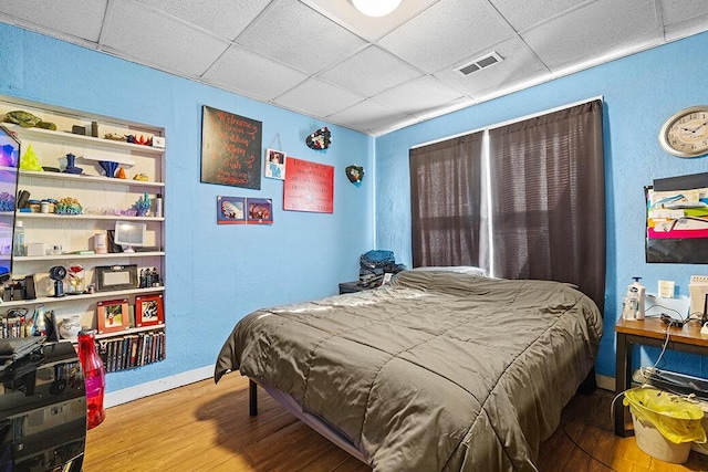 bedroom featuring hardwood / wood-style flooring and a drop ceiling