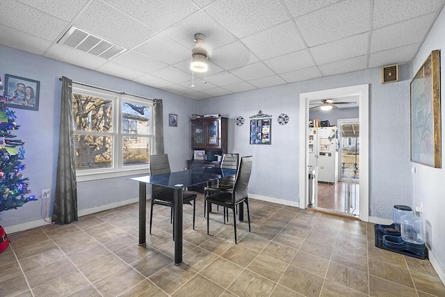 dining area with a paneled ceiling, ceiling fan, and tile patterned flooring