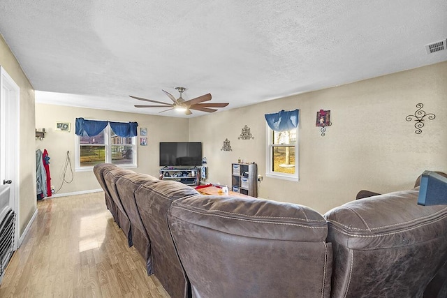 living room with ceiling fan, a textured ceiling, and light hardwood / wood-style flooring