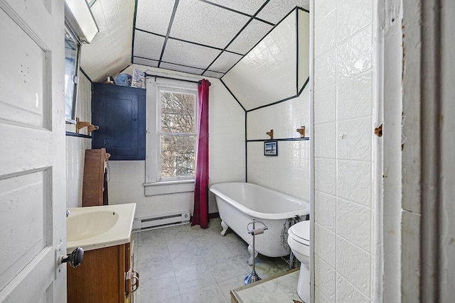 bathroom featuring vanity, vaulted ceiling, a baseboard heating unit, a bath, and toilet