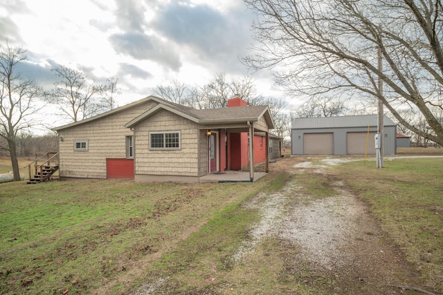 view of front of house featuring a garage, an outdoor structure, and a front yard