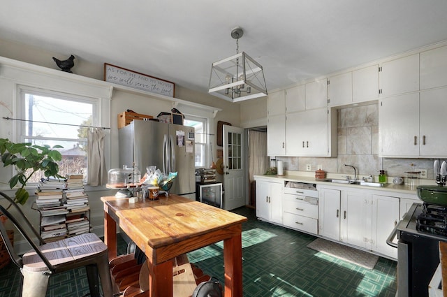 kitchen featuring white cabinets, pendant lighting, stainless steel refrigerator, and sink